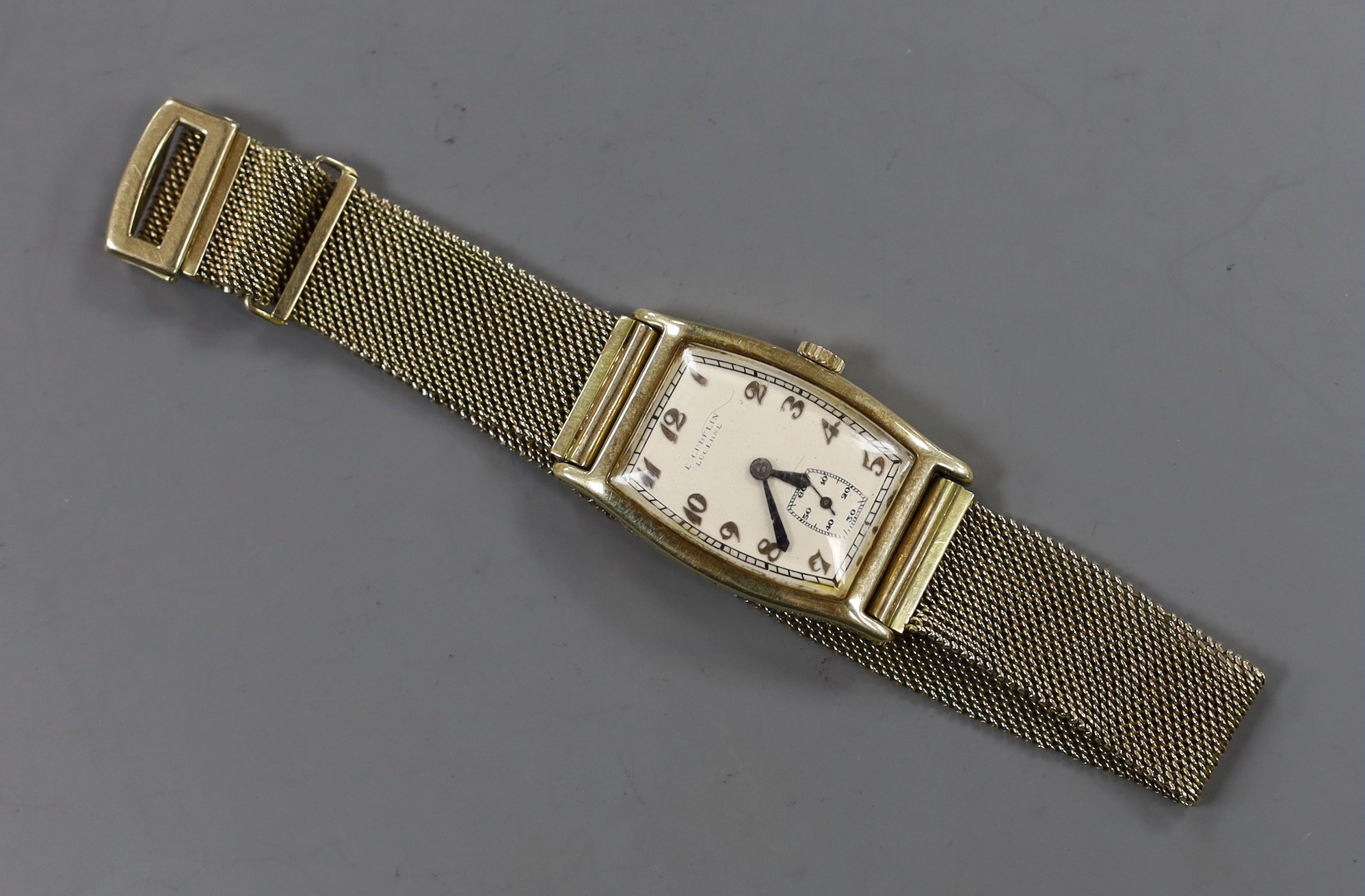 A gentleman's 14k tonneau shaped manual wind wrist watch, retailed by E. Cubelin, with Arabic dial and subsidiary seconds, on associated 9ct gold mesh link bracelet